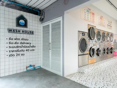 a laundry room with four washing machines on the wall at Wash House Chatuchak in Bangkok