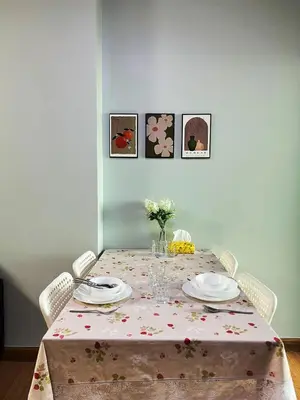 a dining room table with a table cloth with plates and flowers at Tranquil Urban Retreat at Cheangwattana in Pak Kret