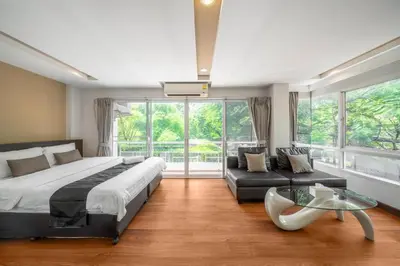 a bedroom with a bed and a couch and a glass table at Story At Bangkok- 211 Studio with Balcony in Khlong Toei