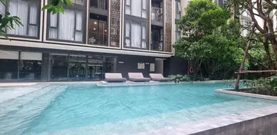 a large swimming pool with chairs and a building at Modern room with Pool and Gym in the city center just 600m from Subway station! in Bangkok