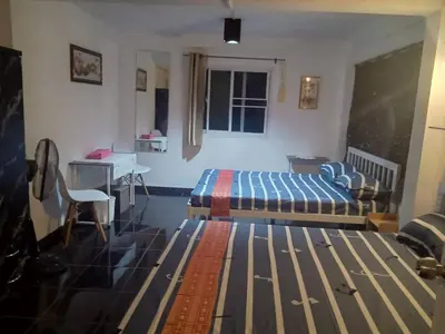 a bedroom with a bed and a table and a desk at Jay Jay Guesthouse in Bangkok