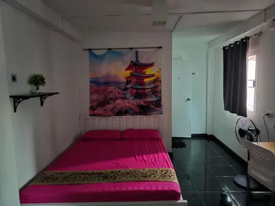 a bedroom with a pink bed with a painting on the wall at Jay Jay Guesthouse in Bangkok