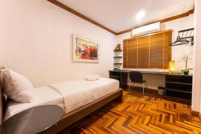 a bedroom with a bed and a desk and a window at Mak Sukhumvit 15 in Bangkok