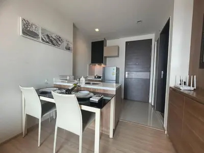 a kitchen with a table and white chairs in a room at Opulence Riverview with Train Access in Bangkok