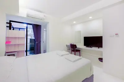 a white bedroom with a bed and a tv at Quite Grove Hotel in Bangkok