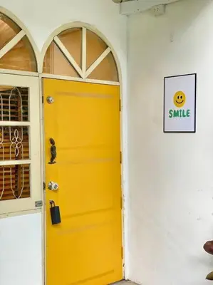 a yellow door on a white wall with a smile sign at Entire House 6 people 3Beds 2Baths near BTS Asoke Terminal21 in Bangkok