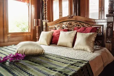 a bedroom with a bed with red and white pillows at เรือนไทยพราวพิมาน Proudpiman Thai Heritage House in Ban Bang Toei (1)