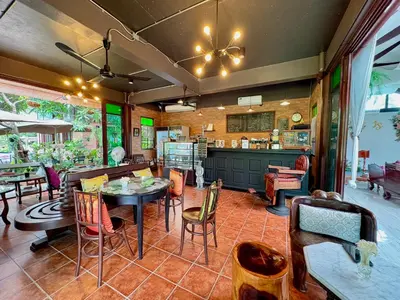 a dining room with tables and chairs and a kitchen at เรือนไทยพราวพิมาน Proudpiman Thai Heritage House in Ban Bang Toei (1)