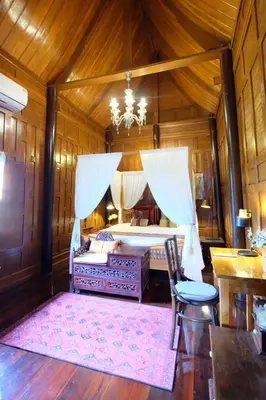 a bedroom with a bed and a chandelier at เรือนไทยพราวพิมาน Proudpiman Thai Heritage House in Ban Bang Toei (1)