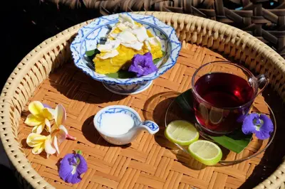 a table with a drink and a bowl of food and flowers at เรือนไทยพราวพิมาน Proudpiman Thai Heritage House in Ban Bang Toei (1)