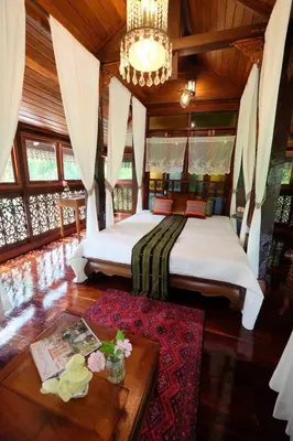 a bedroom with a large bed and a table at เรือนไทยพราวพิมาน Proudpiman Thai Heritage House in Ban Bang Toei (1)