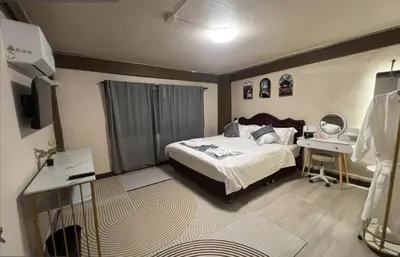 a bedroom with a bed and a desk and a television at Moochi Relax L'Assommior in Bangkok