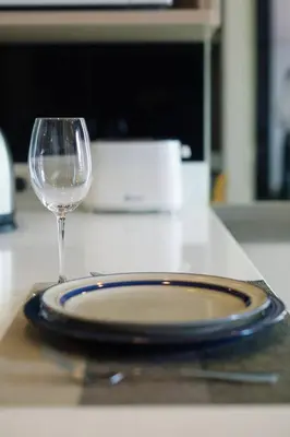 a plate and a wine glass on a counter at Cosy apartment - BTS Phrom phong in Bangkok