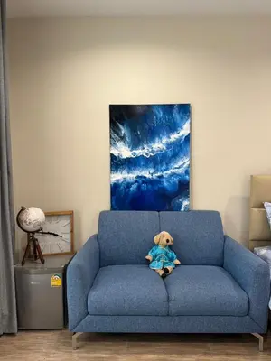 a teddy bear sitting on a blue couch in a room at EM HOME Sukhumvit Bangkok - near Terminal 21, EM District Malls, BTS and MRT Lines in Bangkok
