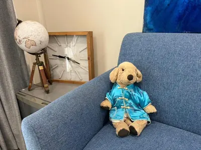 a teddy bear sitting on a blue couch at EM HOME Sukhumvit Bangkok - near Terminal 21, EM District Malls, BTS and MRT Lines in Bangkok
