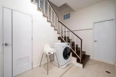 a bathroom with a washing machine under a staircase at 4BR Walk to Chinatown, MRT Luggage Dropoff in Bangkok