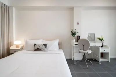 a white bedroom with a bed and a desk and a chair at 4BR Walk to Chinatown, MRT Luggage Dropoff in Bangkok