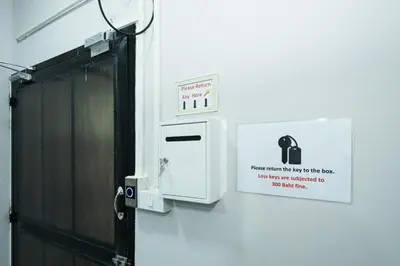 a door with a sign on a wall next to a machine at XX GO INN MRT Hua Lamphong China Town in Bangkok