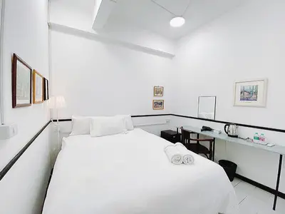 a white bedroom with a bed and a desk at XX GO INN MRT Hua Lamphong China Town in Bangkok