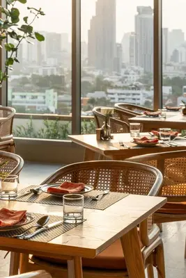 a restaurant with tables and chairs with a view of a city at Somerset Sukhumvit 71 Bangkok in Bangkok