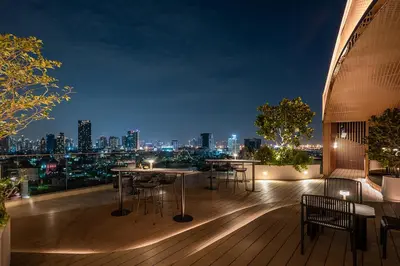 a rooftop deck with tables and chairs at night at Somerset Sukhumvit 71 Bangkok in Bangkok