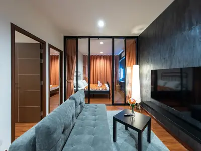 a living room with a blue couch and a bedroom at The City Yaowarat in Samphanthawong