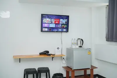 a room with a tv and a refrigerator and stools at GO INN Bangkok Rama3 โกอินน์ พระราม3 in Bangkok