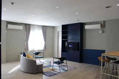 a living room with a couch and chairs and a television at Riva Vibe Hotel Bangkok by PCL in Bangkok
