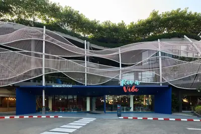 a building with a curved facade with a parking lot at Riva Vibe Hotel Bangkok by PCL in Bangkok