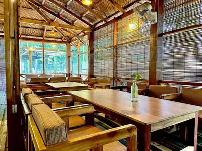 an empty restaurant with wooden tables and chairs at Bruce House in Nonthaburi
