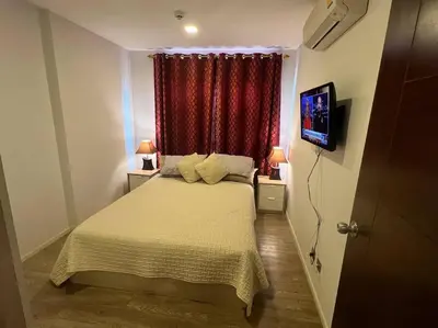 a small bedroom with a bed and a television at Great Value Apartment in Bang Khen