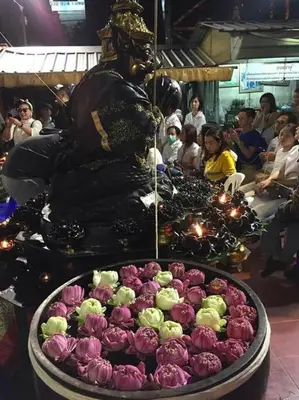 a large bowl of purple and green flowers next to a statue at Cozy 1 Bedroom Apartment Close by Ratchada in Bangkok