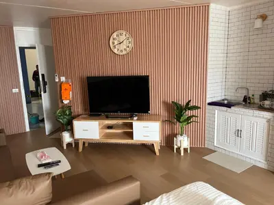 a living room with a tv and a clock on a wall at OpenView เมืองทอง T1 Impact Muang Thong Thani in Nonthaburi