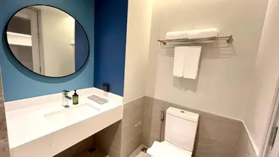 a bathroom with a sink and a toilet and a mirror at The Quarter Ramkhamhaeng by UHG in Bangkok