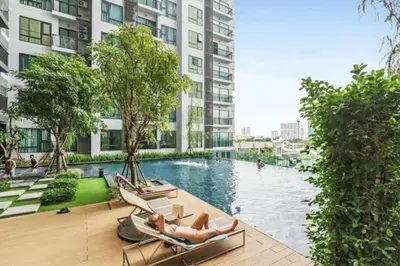 two people laying in chairs by a swimming pool in a building at Thong Lor, Sukhumvit 36 in Bangkok