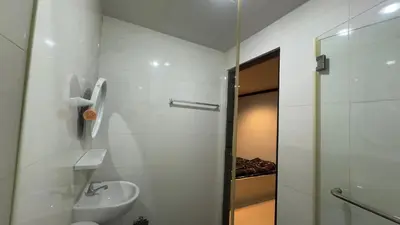 a white bathroom with a sink and a shower at The Haven Sabi in Bangkok