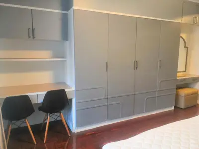 a kitchen with white cabinets and two black chairs at Silom room 40 sqm with 2 Queen beds for 4 persons in Bangkok