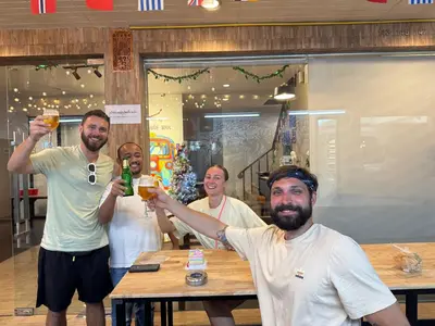 a group of men holding up glasses of beer at The LODGE BKK Hostel in Bangkok