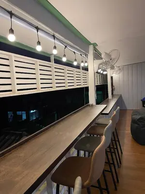 a bar with a row of stools in a room at Green Cabin Hostel in Bangkok