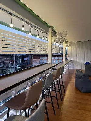 a bar with a row of chairs and a long counter at Green Cabin Hostel in Bangkok