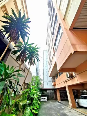 a parking lot with palm trees between two buildings at R Lodge in Bangkok