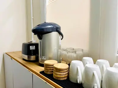 a coffee maker sitting on a counter next to a pile of pancakes at Charming Hostel in Bangkok