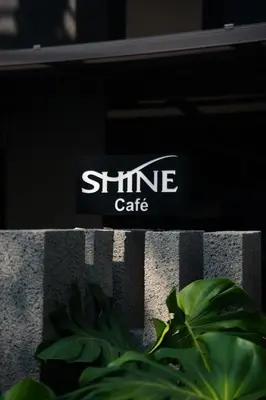 a sign for a shine cafe sitting on a fence at Shine Aparthotels Sukhumvit Thonglor in Bangkok