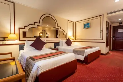 a hotel room with two beds and a mirror at Grace Hotel in Bangkok