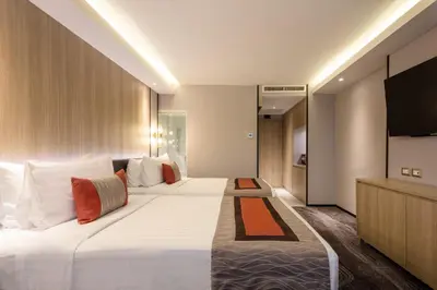 a hotel room with two beds and a flat screen tv at Grace Hotel in Bangkok