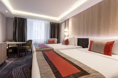 a hotel room with two beds and a table at Grace Hotel in Bangkok