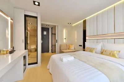 a white bedroom with a large bed and a bathroom at Victora Hostel in Bangkok
