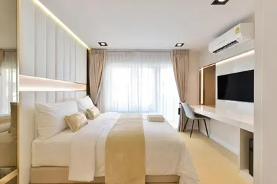 a bedroom with a bed and a desk and a television at Victora Hostel in Bangkok