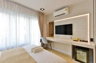a hotel room with a bed and a desk with a television at Victora Hostel in Bangkok