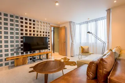 a living room with a couch and a flat screen tv at PETRA Designer Apartment Sukhumvit, Nana BTS in Bangkok